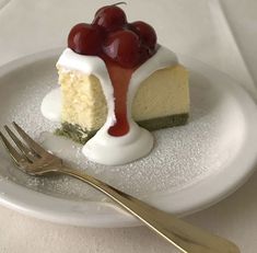 a piece of cheesecake with cherries on top sits on a plate next to a fork