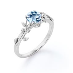 an engagement ring with a blue topazte and leaves on the side, set in white gold