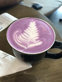 a cappuccino with a leaf drawn on the foam is sitting on a table