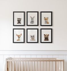 a baby crib with four framed pictures on the wall