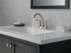 a bathroom sink with a faucet, soap dispenser and mirror