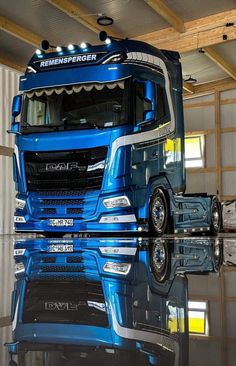 a blue semi truck parked in a garage next to a wall with mirrors on it