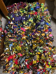 a pile of multicolored scarves sitting on the floor next to a chair