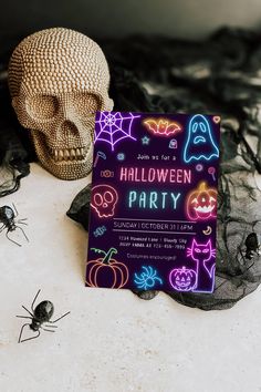 a halloween party card sitting on top of a table next to a skull and spider