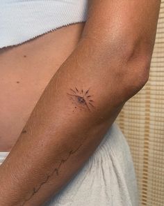 a woman's arm with a small sun tattoo on the back of her left arm