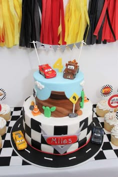 the birthday cake is decorated with cars and race flags