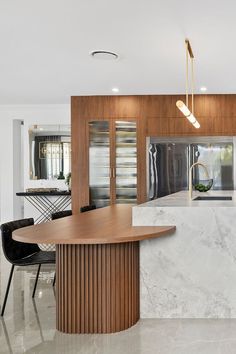 a modern kitchen with marble counter tops and wooden cabinetry, along with black chairs