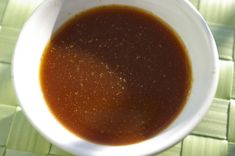 a white bowl filled with brown liquid on top of a green tablecloth covered floor