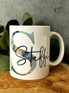 a white coffee mug with the word steff on it sitting on a wooden table