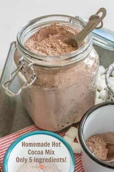 homemade hot cocoa mix in a glass jar with ingredients around it on a metal tray