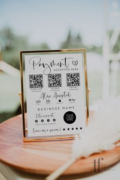 a sign that is on top of a wooden table next to a white and black feather