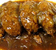 meatballs covered in gravy and onions on top of a white plate with yellow border