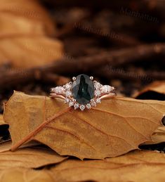 an oval cut green tourmaline surrounded by white diamonds sits on top of a leaf