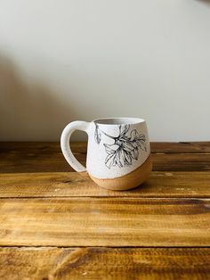 a white and brown coffee cup sitting on top of a wooden table