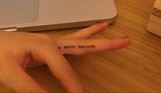 a person's hand with a small tattoo on it, next to a laptop