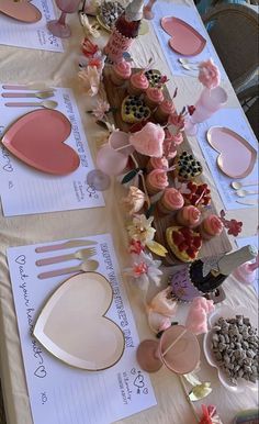 a table topped with lots of cupcakes and paper hearts on top of it