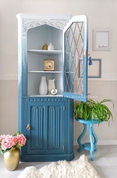 a blue china cabinet sitting next to a potted plant on top of a white rug