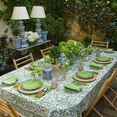 a table set with plates and vases in the middle of an outdoor dining area