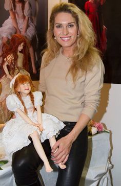 a woman holding a doll sitting on top of a table