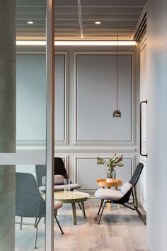 a room with chairs, tables and a plant in the corner on the wall next to it