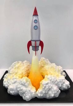 a toy rocket launching into the sky with clouds on it's back and bottom