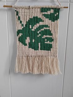 a green and white woven wall hanging on a wooden hanger next to a door