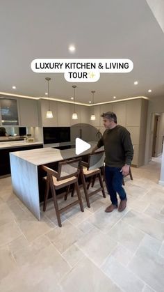 a man standing in a kitchen next to a dining room table with chairs on it