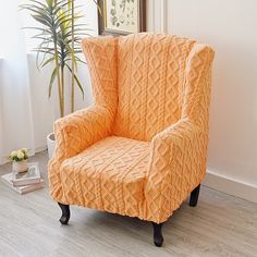 an orange chair sitting on top of a hard wood floor next to a potted plant