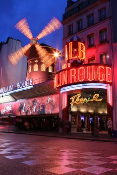 a large building with neon lights on it's sides and a windmill in the middle