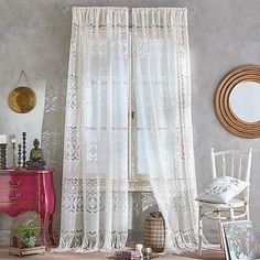 a living room filled with furniture and a white window curtain hanging from the side of a wall