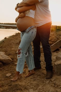 a pregnant woman is hugging her husband on the beach