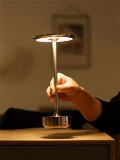 a person holding a metal object on top of a wooden table