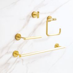 two brass bathroom accessories on a white marble countertop with gold handles and bars in the shape of rectangles