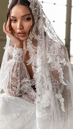 a woman in a wedding dress with a veil over her head and hands on her face