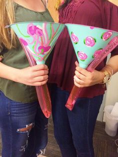 two women are holding up pink and blue paper cones that look like they have hearts on them