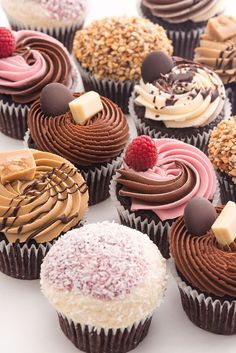 many different cupcakes with chocolate frosting and toppings