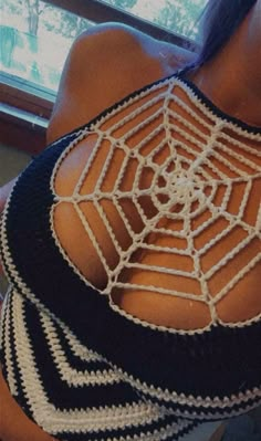 the back of a woman's top with a spider web design on her chest