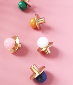 four pairs of rings with different colors on a pink background, one is gold and the other is green