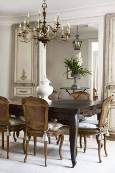 an elegant dining room with chandelier, chairs and large wooden table in the center