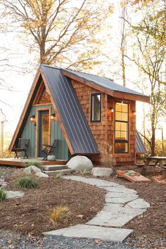 a small cabin in the woods with a walkway leading up to it's front door