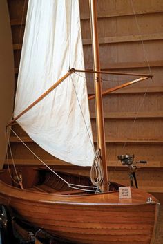 a wooden sailboat sitting on display in a room with wood paneling and stairs