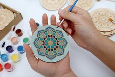 a person is holding a paper plate with a flower design on it, surrounded by other crafting supplies