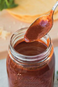 a spoon full of bbq sauce on top of a jar with a wooden spoon