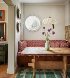 a table with flowers in a vase on top of it next to a bench and lamp