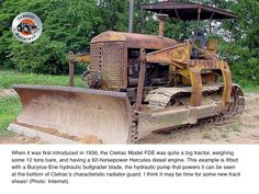 an old bulldozer sitting in the middle of a field next to some trees