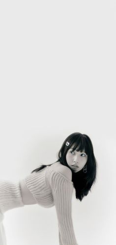 a woman with black hair and white stockings posing for the camera in front of a white wall