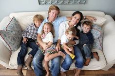 a family is sitting on a couch with their arms around each other and smiling at the camera