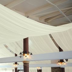 the ceiling is covered with white draping and lights are hanging from it's sides