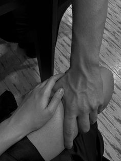 two people holding each other's hands while sitting on the floor in front of a table