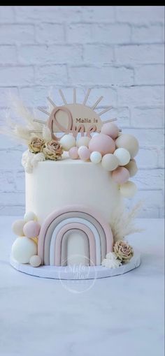 a white cake with pink and gold decorations on it's top, sitting on a table